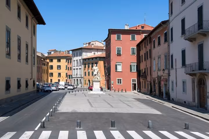 Sunny Pisa piazza with colorful historic buildings and statue perfect for a self-guided mystery puzzle walking tour