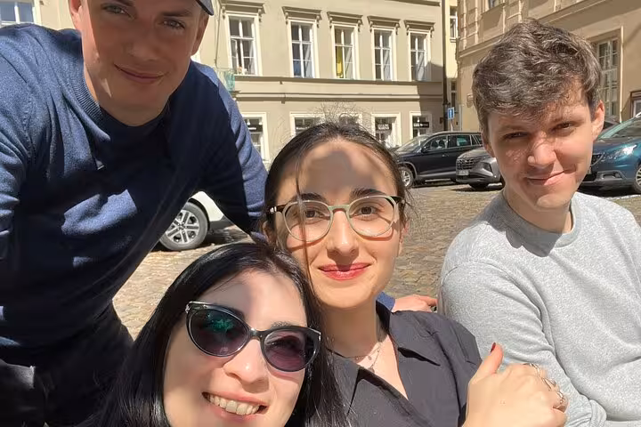 Group of four friends enjoying a sunny Prague self-guided walking tour with outdoor escape game in the Old Town