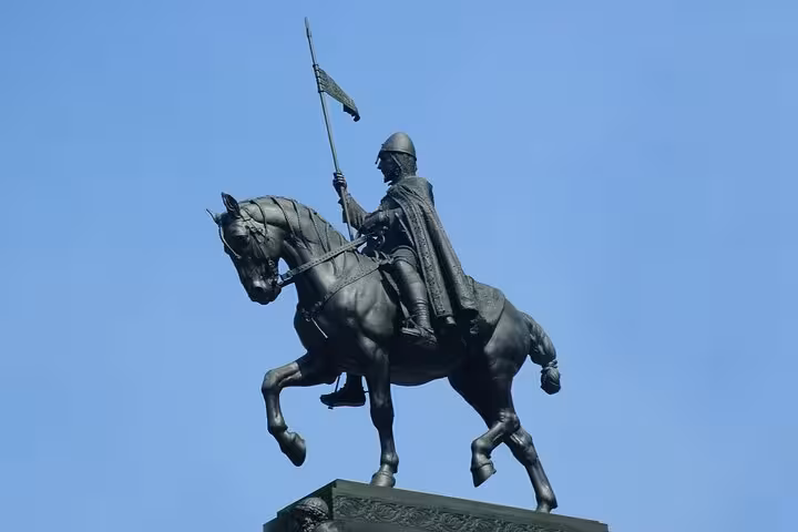 Bronze equestrian statue of Saint Wenceslas holding a lance against a clear blue sky in Prague