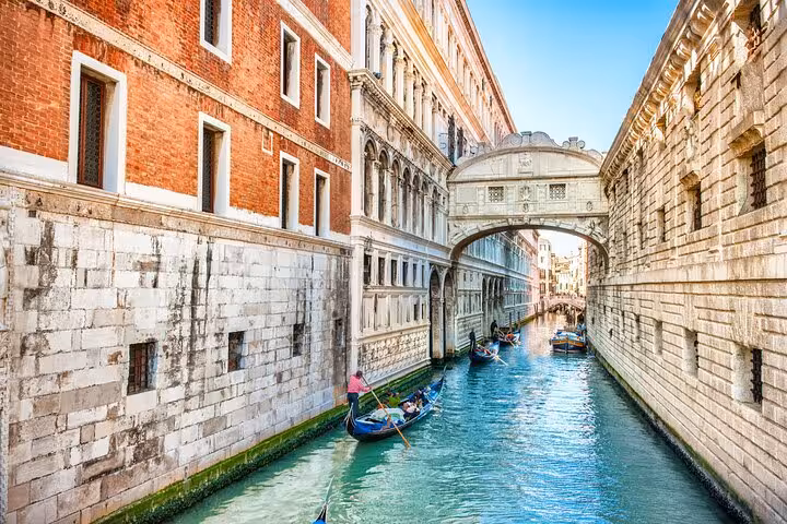 Gondolas gliding under the Bridge of Sighs on Venice canal during a romantic Casanova walking tour