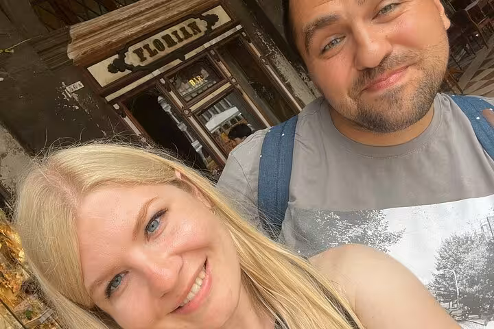 Smiling couple posing outside historic Caffè Florian in Venice on a Casanova self-guided romance game tour