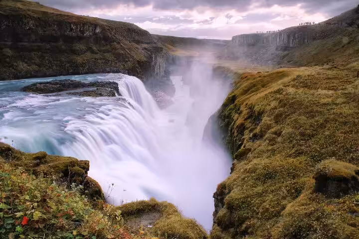 Gullfoss waterfall cascading into a misty canyon with moss-covered cliffs on Iceland's Golden Circle