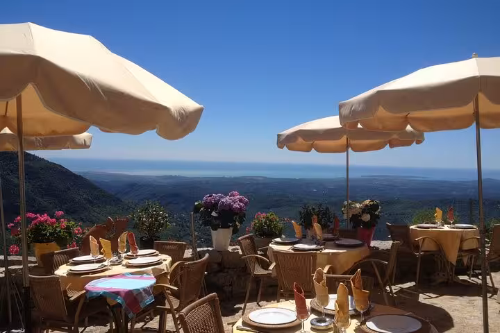 Scenic view of a picturesque French village on a hill, surrounded by lush greenery under a vibrant blue sky.