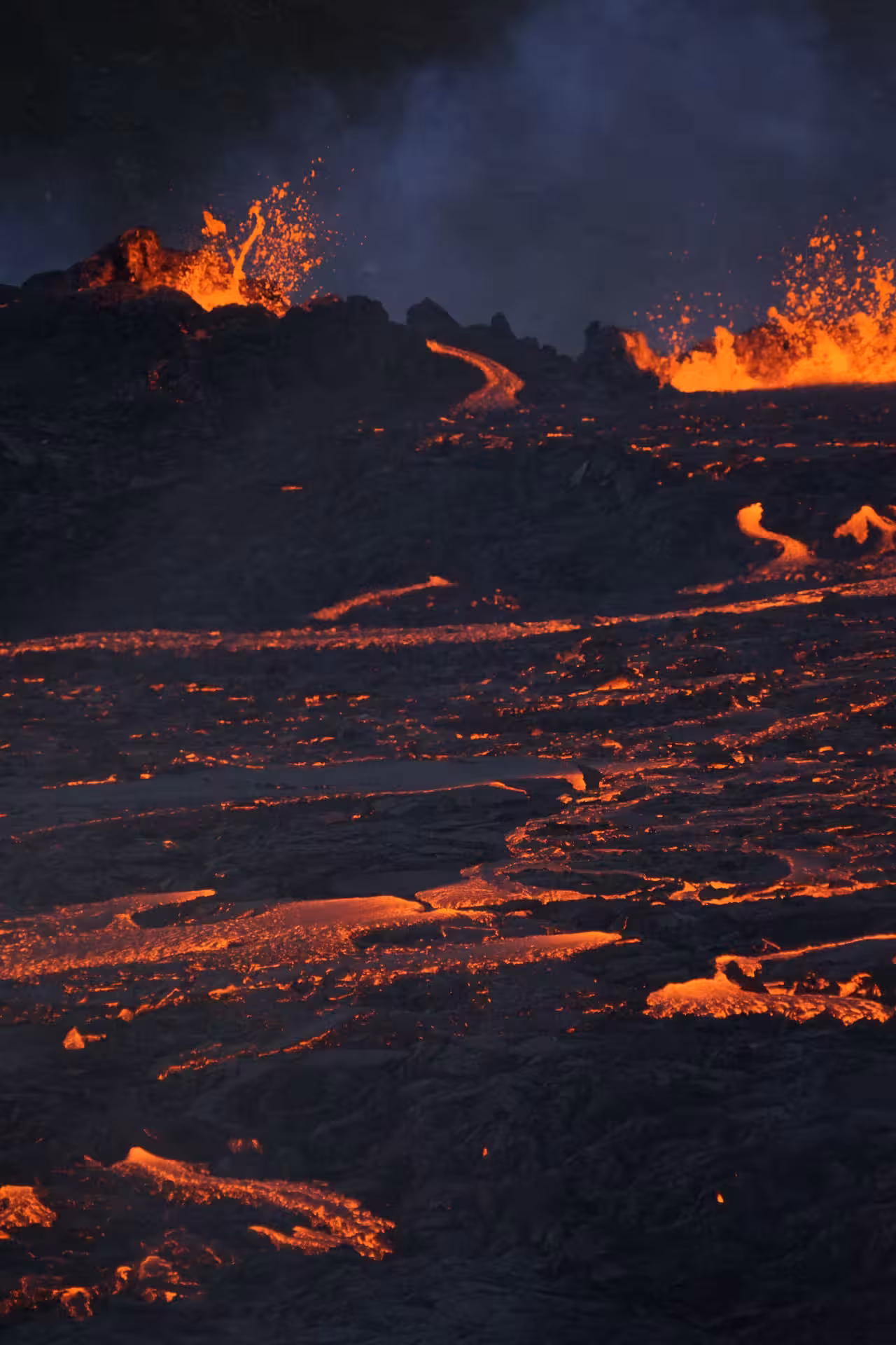 Glowing lava streams cascading down dark volcanic rock face during Reykjanes Peninsula eruption