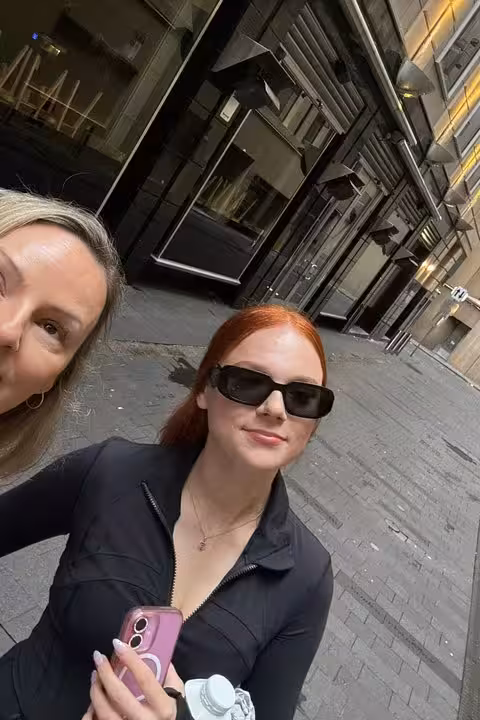 Two women posing for a selfie on a Sydney city street near historic buildings