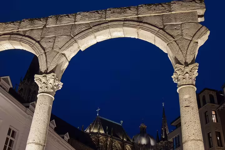Stone arch at night framing Aachen Cathedral rooftops, highlight on an Aachen self-guided scavenger hunt tour