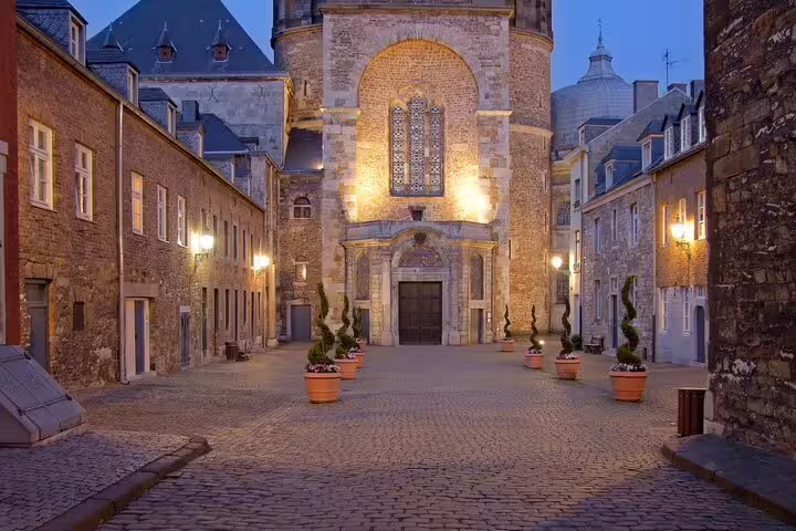 Evening view of cobblestone lane to a lit historic church in Aachen, part of a self-guided scavenger hunt