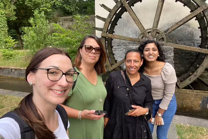Smiling travelers at Aarau old waterwheel stop on a smartphone self-guided scavenger hunt city tour