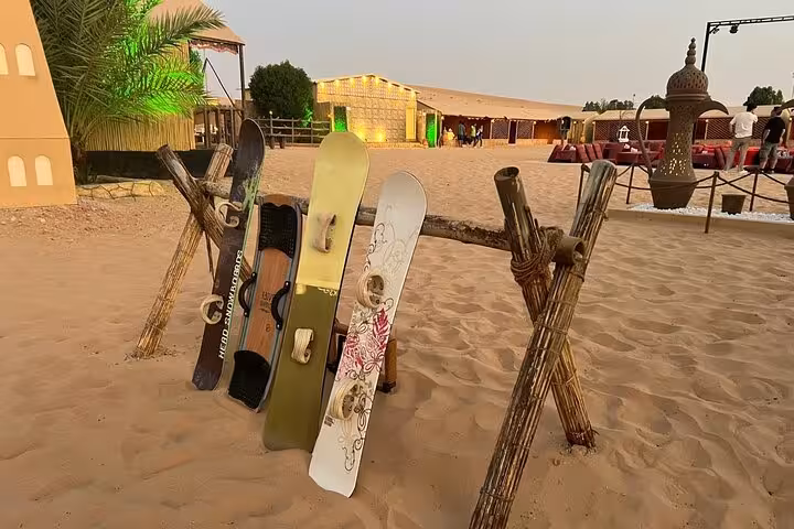 Sandboards displayed on a wooden rack at Abu Dhabi desert safari camp ready for dune sandboarding adventure