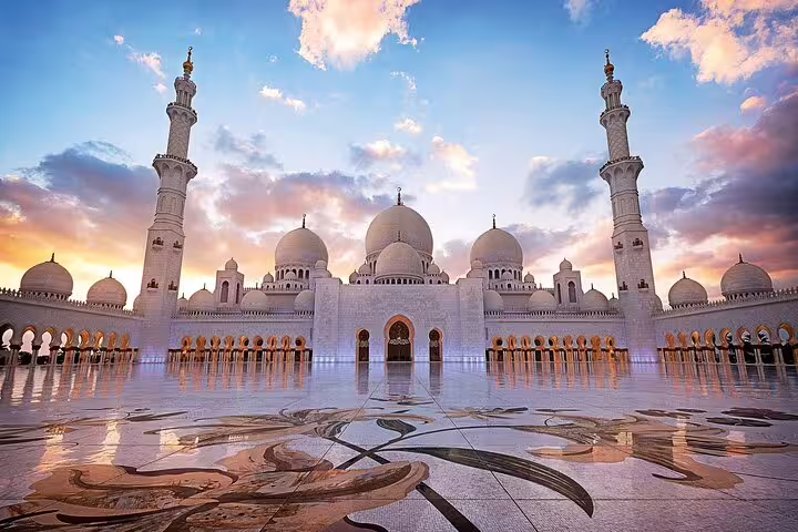 The Sheikh Zayed Grand Mosque at sunset, featuring intricate architecture and a reflective marble courtyard.