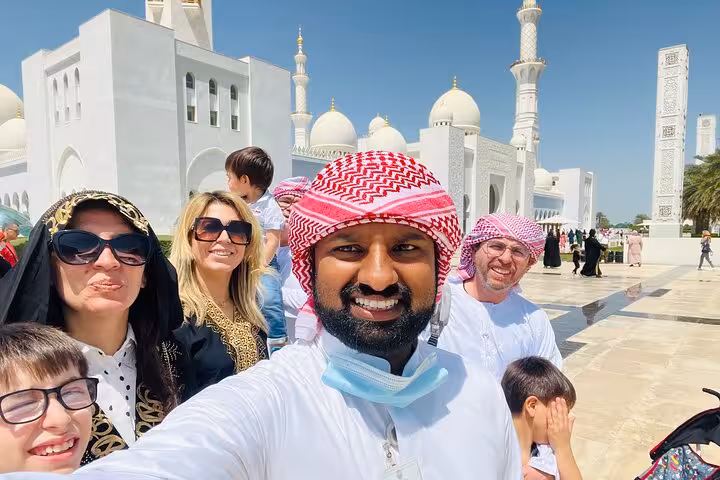 Tour guide and tourists taking a selfie at Sheikh Zayed Grand Mosque on a full-day Abu Dhabi sightseeing tour