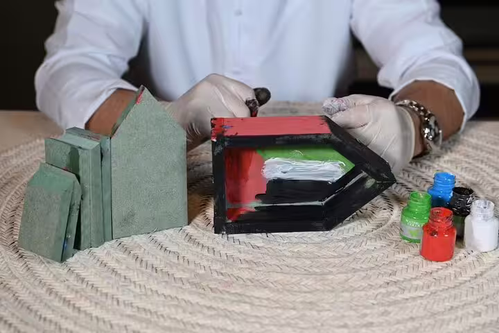 Guest painting a house-shaped souvenir in UAE flag colours during Abu Dhabi guided tour with Qasr Al Watan visit and lunch