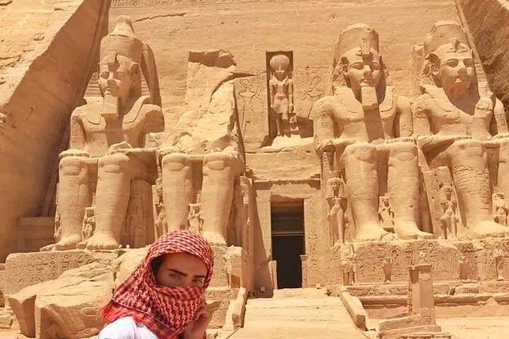 Abu Simbel Great Temple facade with colossal Ramses II statues, visitor on Aswan to Abu Simbel day trip