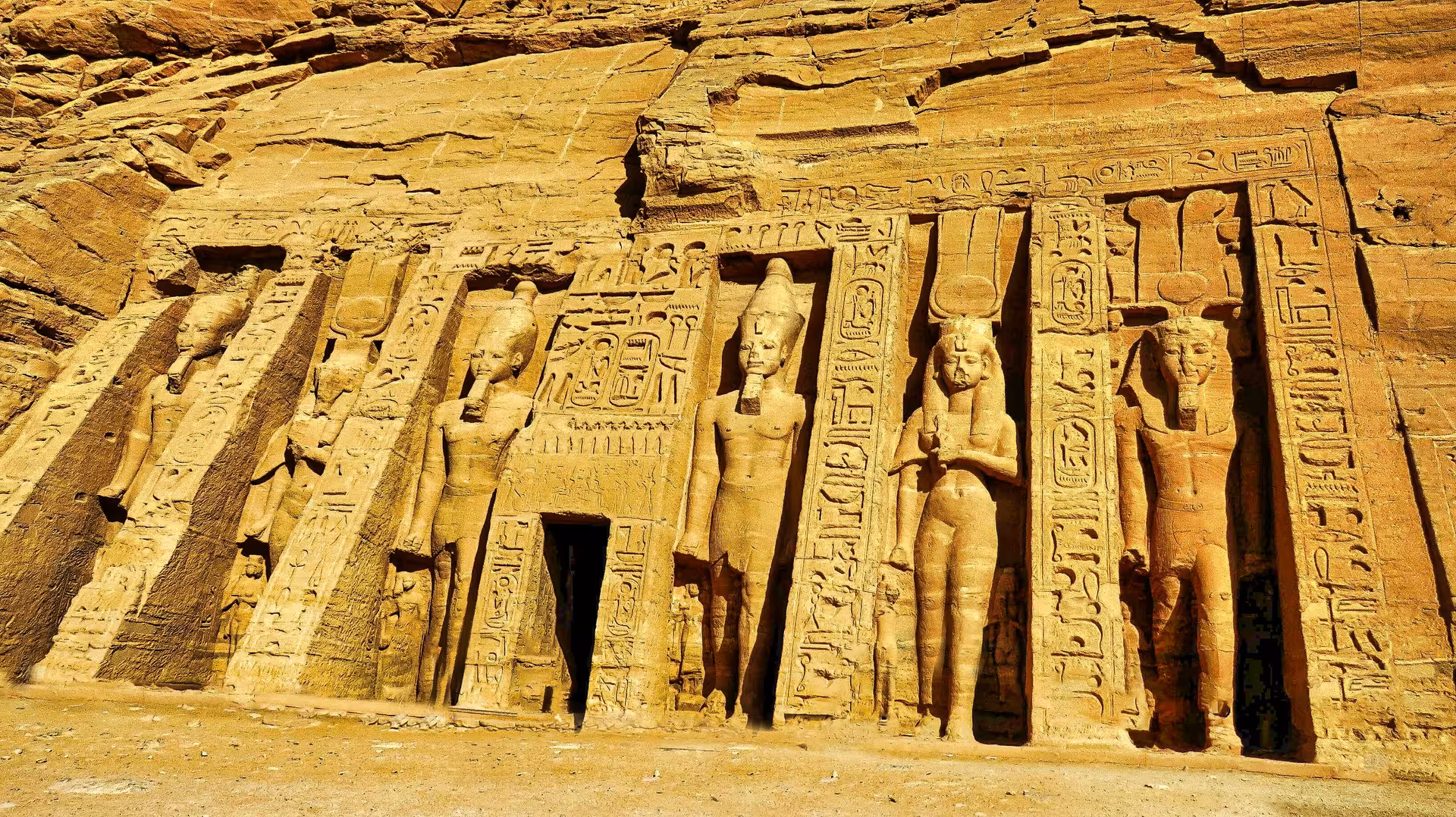 Rock-cut facade of Abu Simbel Small Temple with colossal statues of Ramesses II and Nefertari carved into sandstone cliff