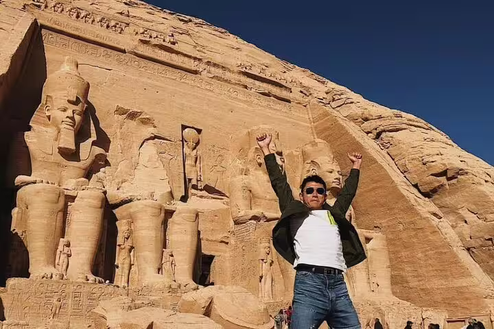 Tourist posing before Abu Simbel Great Temple façade, private Aswan to Abu Simbel tour with guide and transfers