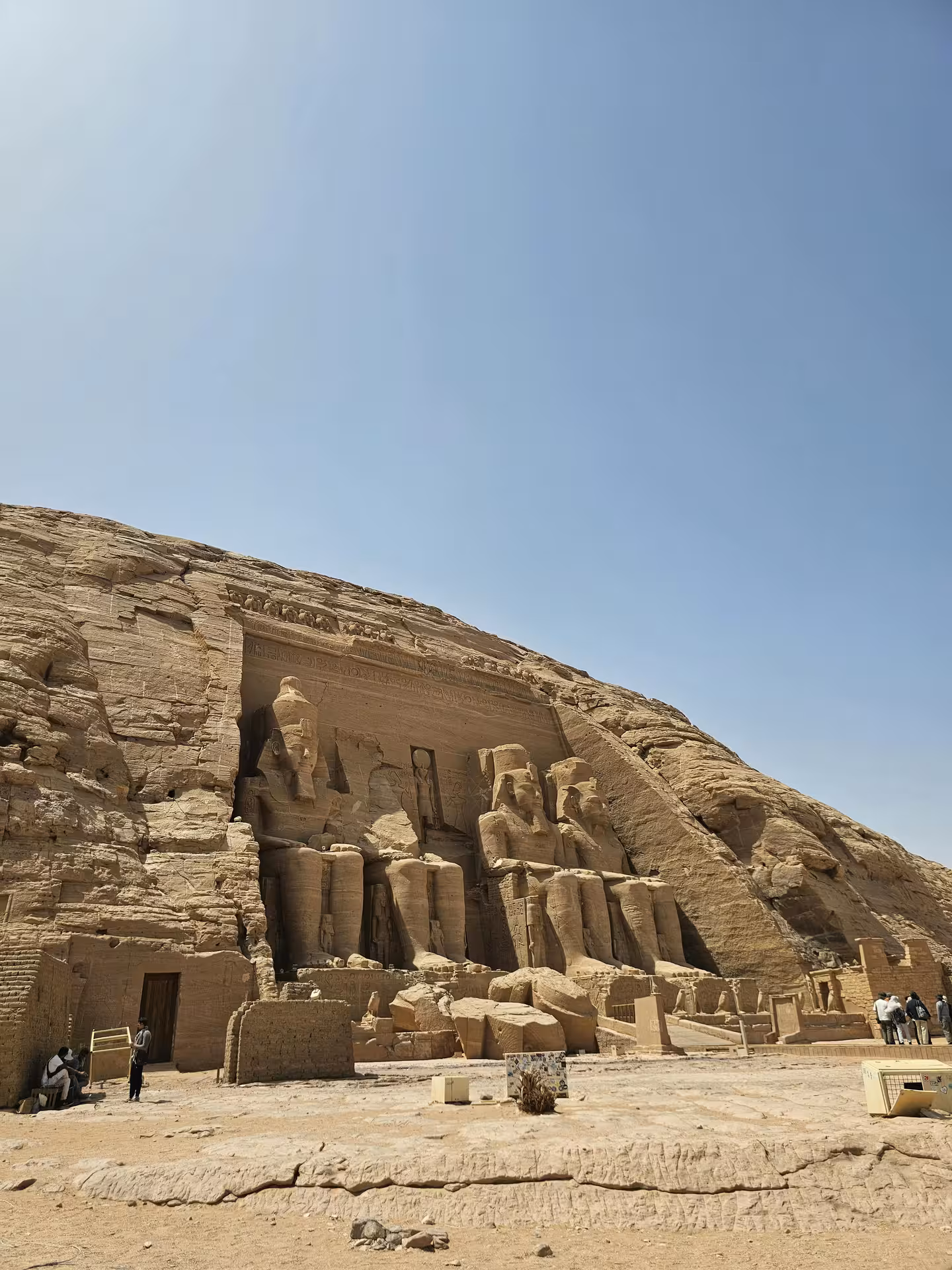 Massive rock-cut facade of Abu Simbel Temple with four colossal statues of Ramesses II under clear blue sky