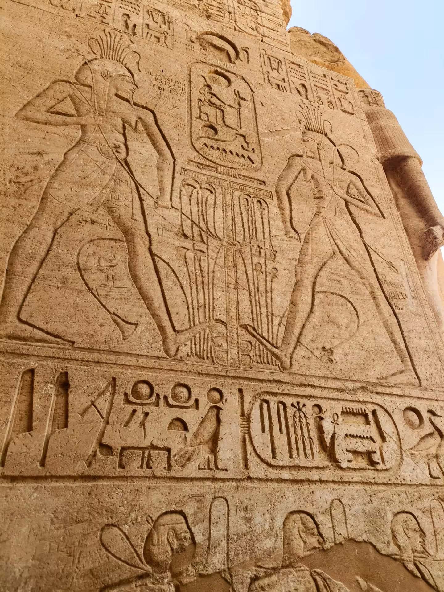 Ancient Egyptian hieroglyphic carvings and deity reliefs on sandstone wall at Abu Simbel temple