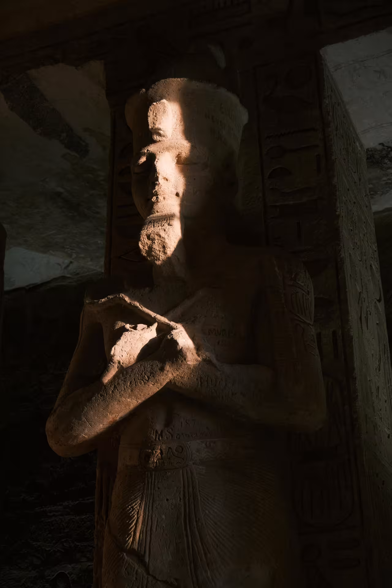 Ancient Egyptian pharaoh statue inside Abu Simbel Temple illuminated by dramatic lighting