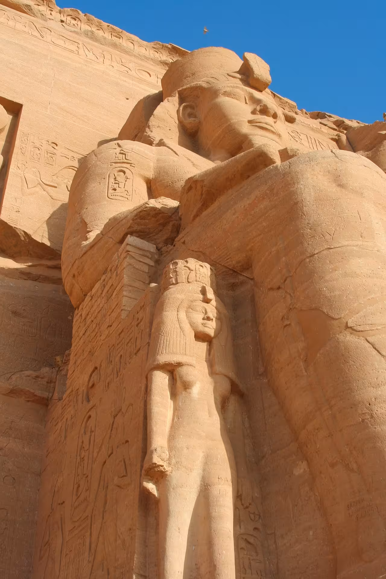 Colossal statues of Ramesses II and Queen Nefertari carved into the sandstone facade of Abu Simbel Temple, Egypt