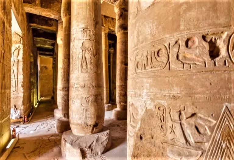 Ancient carved stone pillars and hieroglyphs in Abydos Temple corridor on full-day Dendera and Abydos day trip