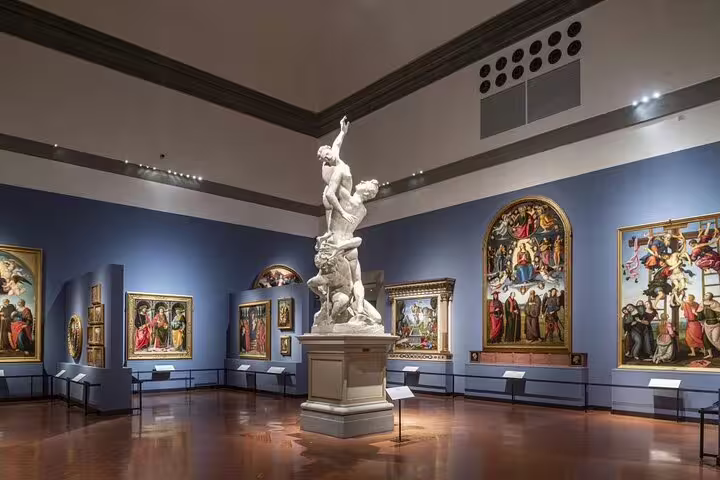 Renaissance paintings and marble sculpture displayed in a grand hall of Florence’s Academia Gallery on a guided art tour
