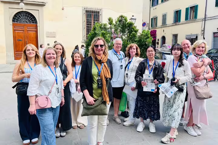 Happy tour group with headsets and passes gathered outside Florence’s Academia Gallery before a live guided visit