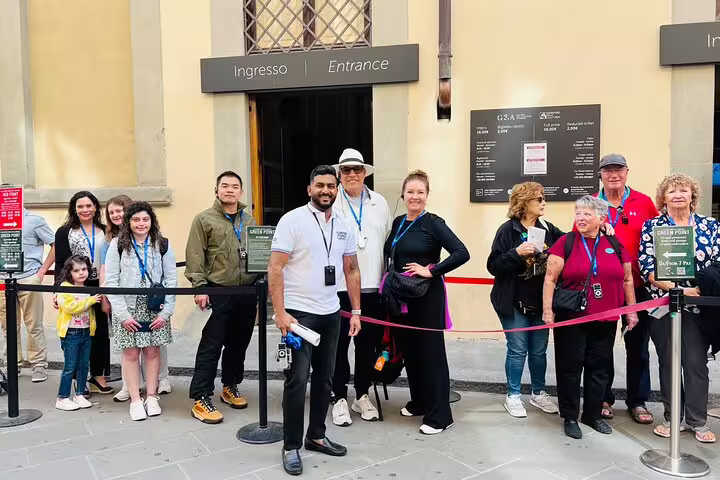 Small group with guide using skip-the-line tickets at Academia Gallery entrance in Florence for a live guided tour experience