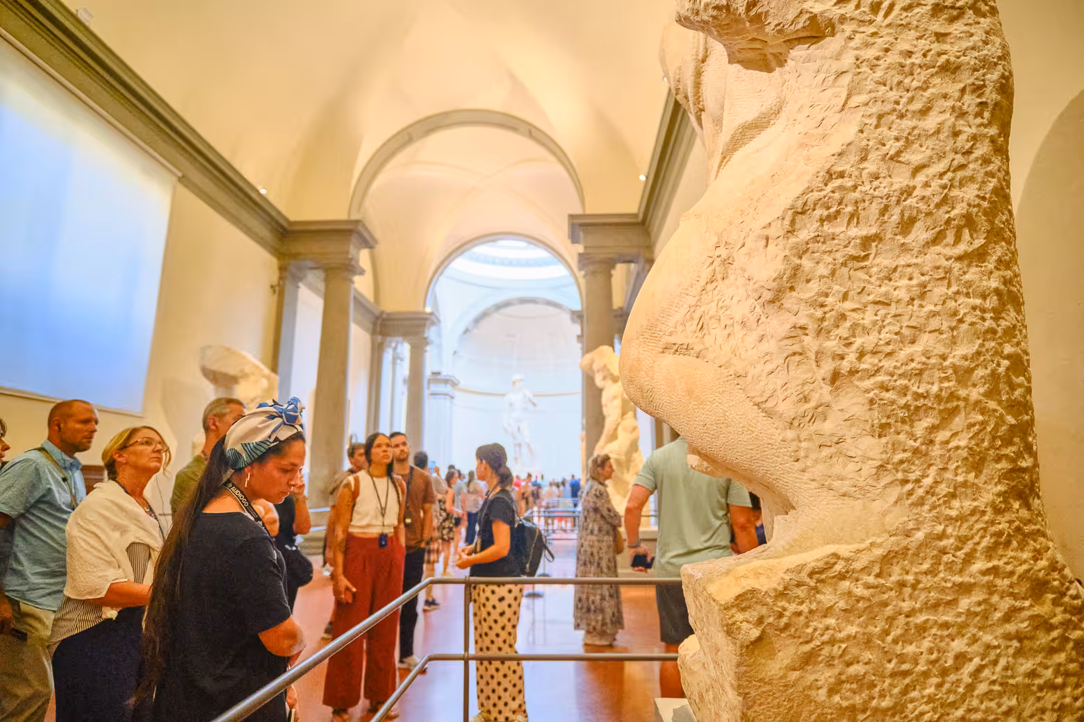 Tourists explore sculptures in Accademia Gallery, Florence, during a skip-the-line guided tour featuring David.