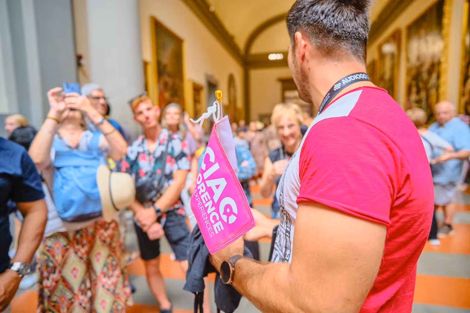 Guide leads visitors through Accademia Gallery with Florence tour flag in hand.