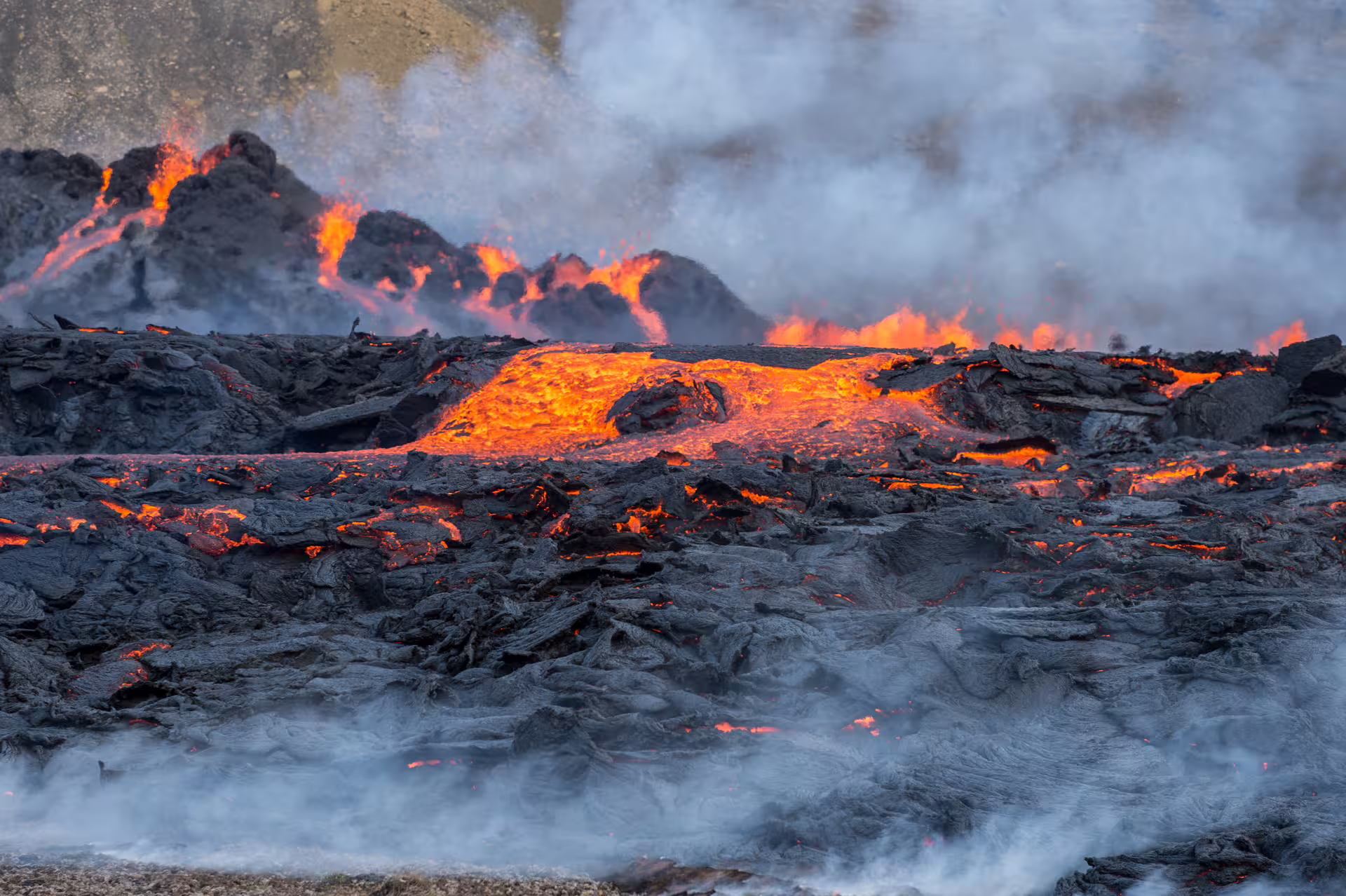 Active lava flow with glowing orange molten rock and volcanic smoke during Iceland volcano eruption