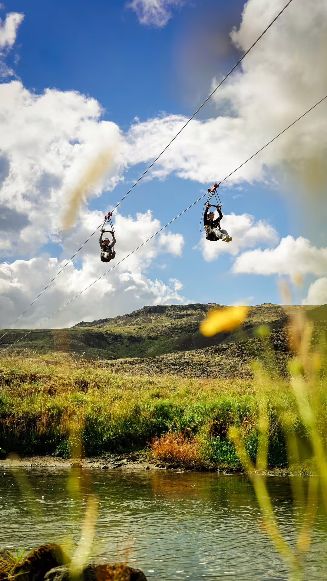 Thrill-seekers zipline over lush landscapes under a bright sky during the Adrenaline Combo Off-Road Buggy & Mega Zipline Experience.