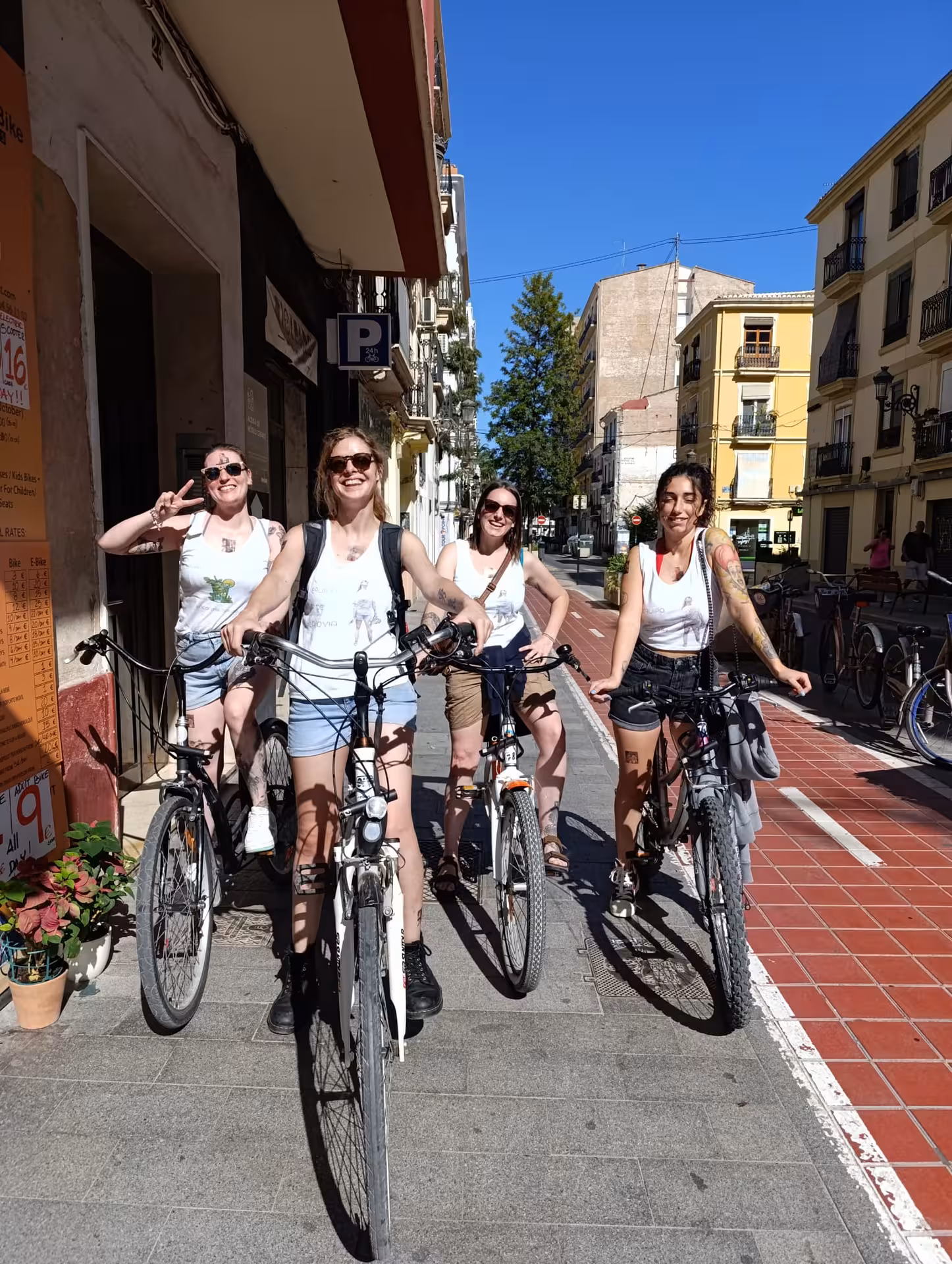 Group of friends posing with adult city bike rentals on a sunny Valencia street, perfect for city cycling