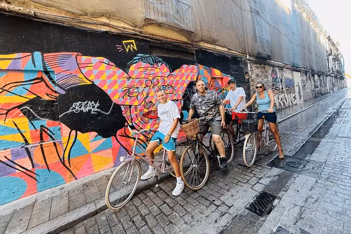 Group on adult city bike rentals riding past colorful street art, a fun self-guided urban cycling experience