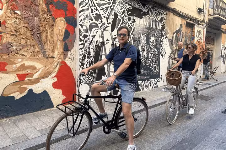Adult city bike rental riders passing street art murals in a historic neighborhood, perfect for urban sightseeing