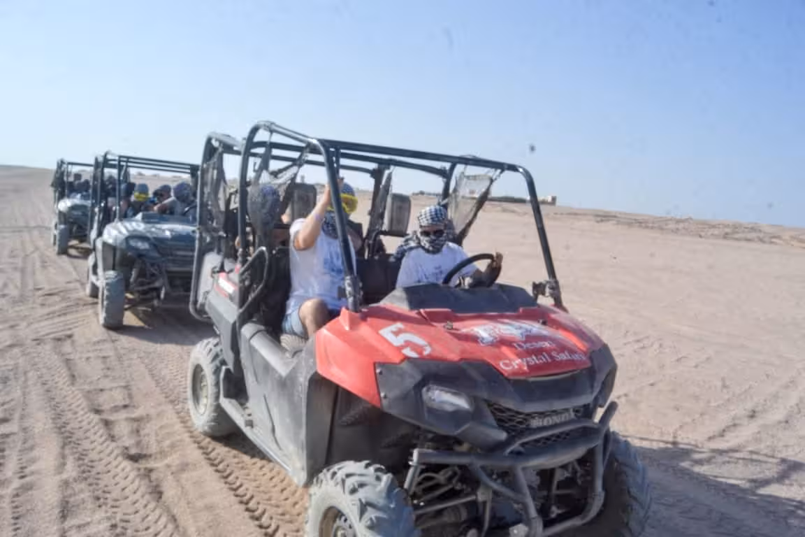 Adults riding buggy vehicles through sandy desert terrain on a quad bike safari tour in Soma Bay