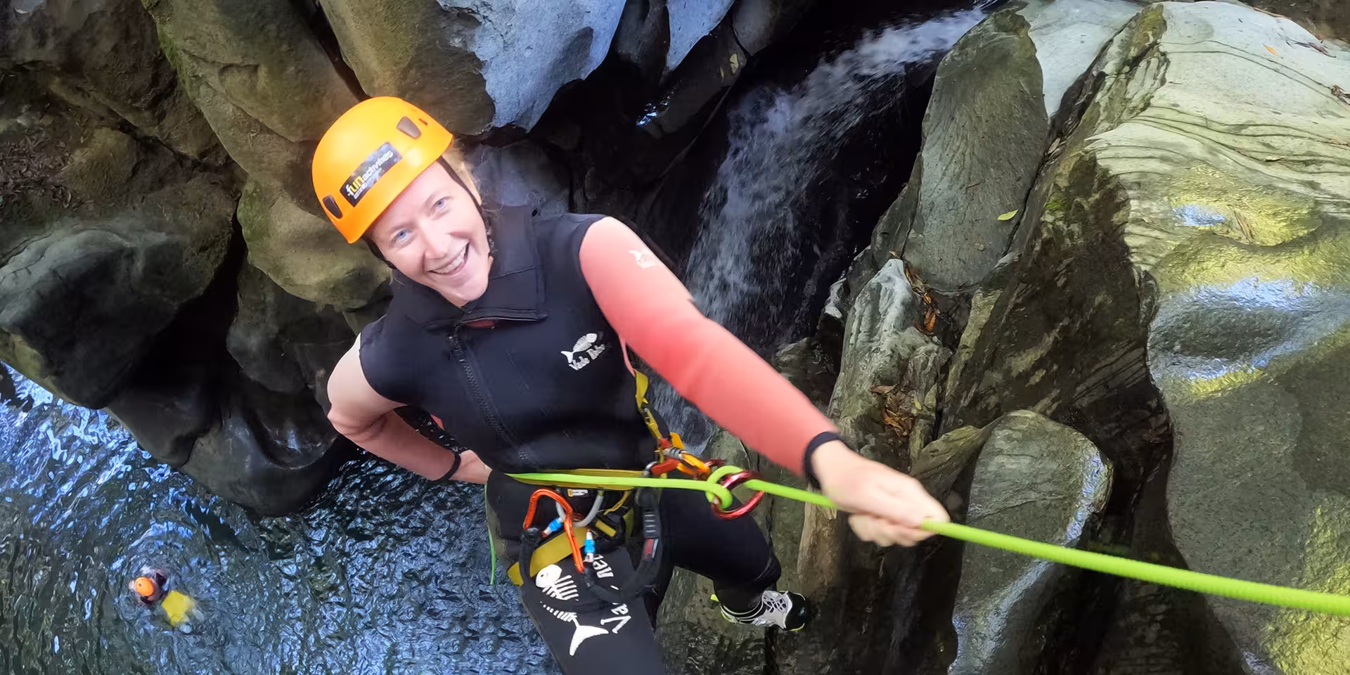 Smiling adventurer abseiling beside Salto do Cabrito waterfall in São Miguel Azores canyoning experience