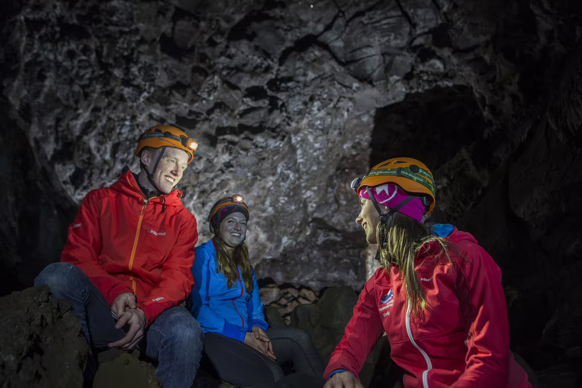 Adventurers explore a cave, wearing helmets and jackets, showcasing an exciting ATV and caving tour experience.