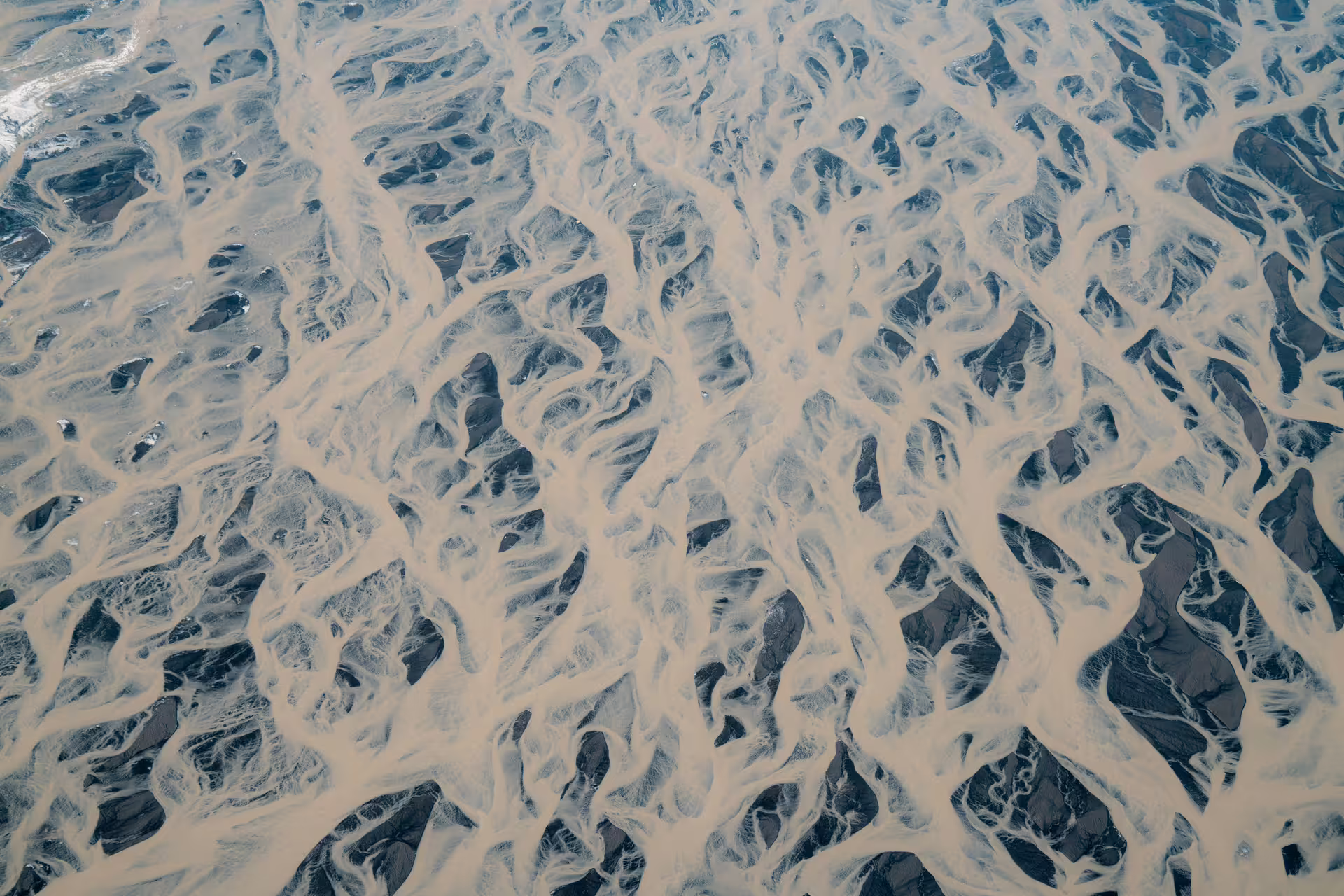 Aerial view of braided glacial river delta with sandy channels and dark water in South Iceland