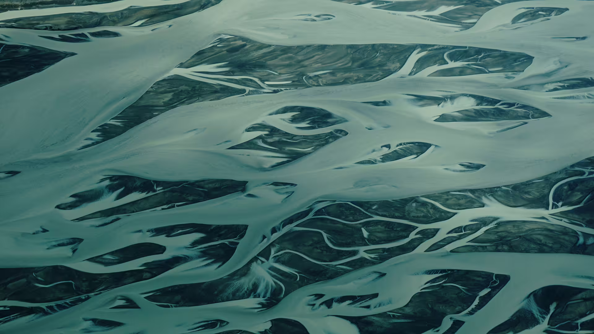 Aerial view of braided glacial rivers forming intricate patterns across Iceland's South Coast landscape