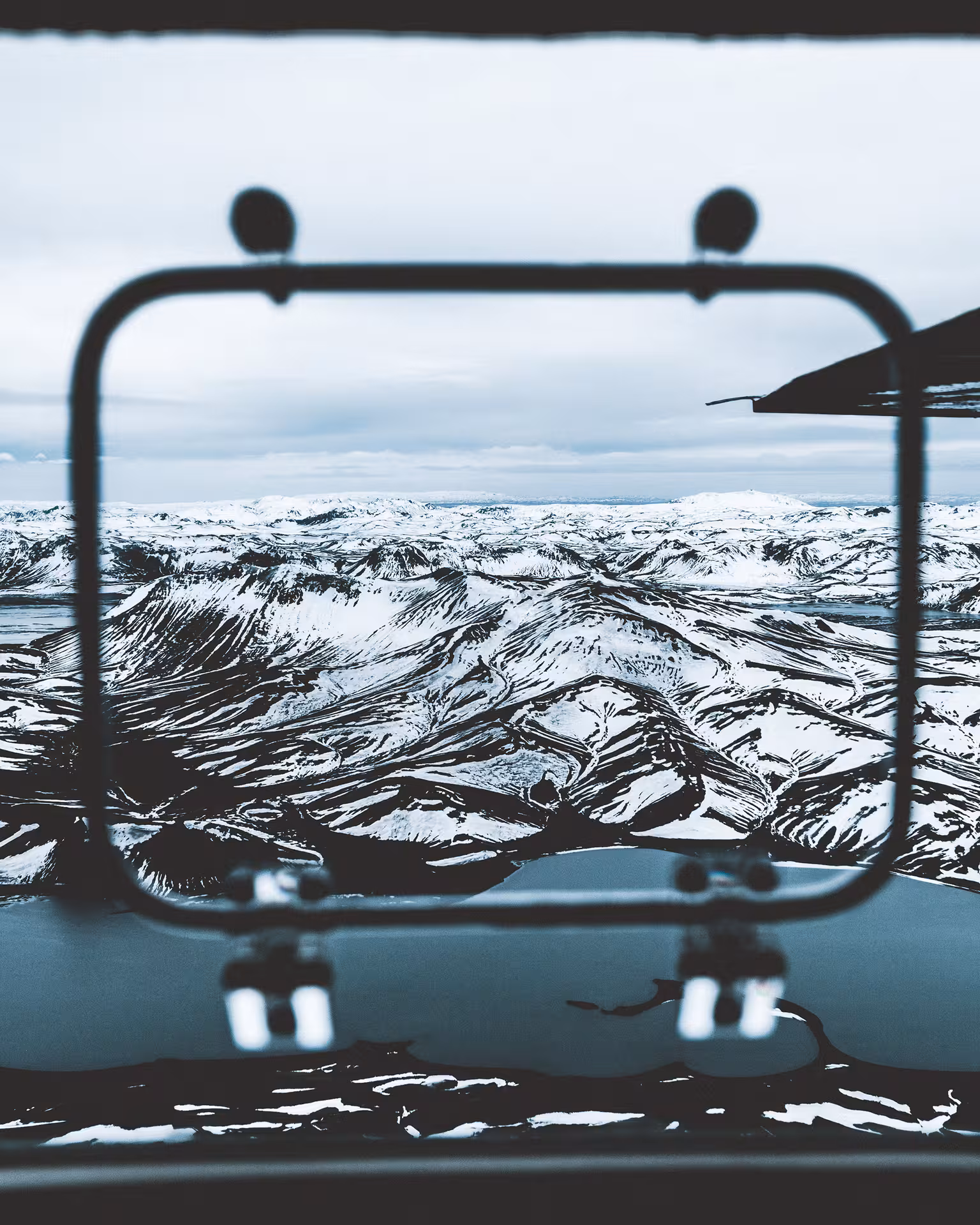 Aerial view of snow-covered Iceland highlands mountains seen through a small aircraft window during a private flight