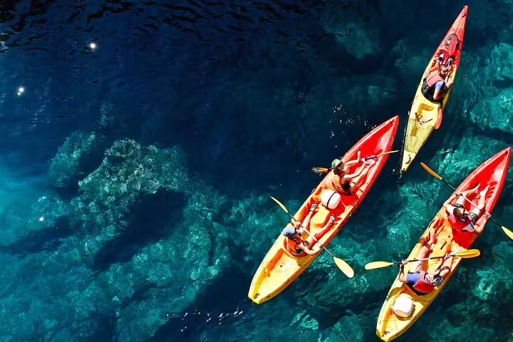 Aerial view of sea kayakers paddling over crystal-clear reefs on a sea kayaking and snorkeling tour