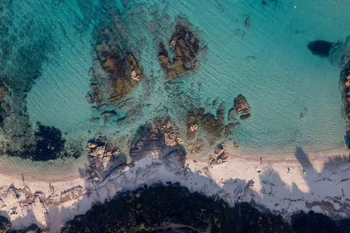Aerial view of turquoise Mediterranean waters with rocky coastline and white sandy beach near Saint Tropez