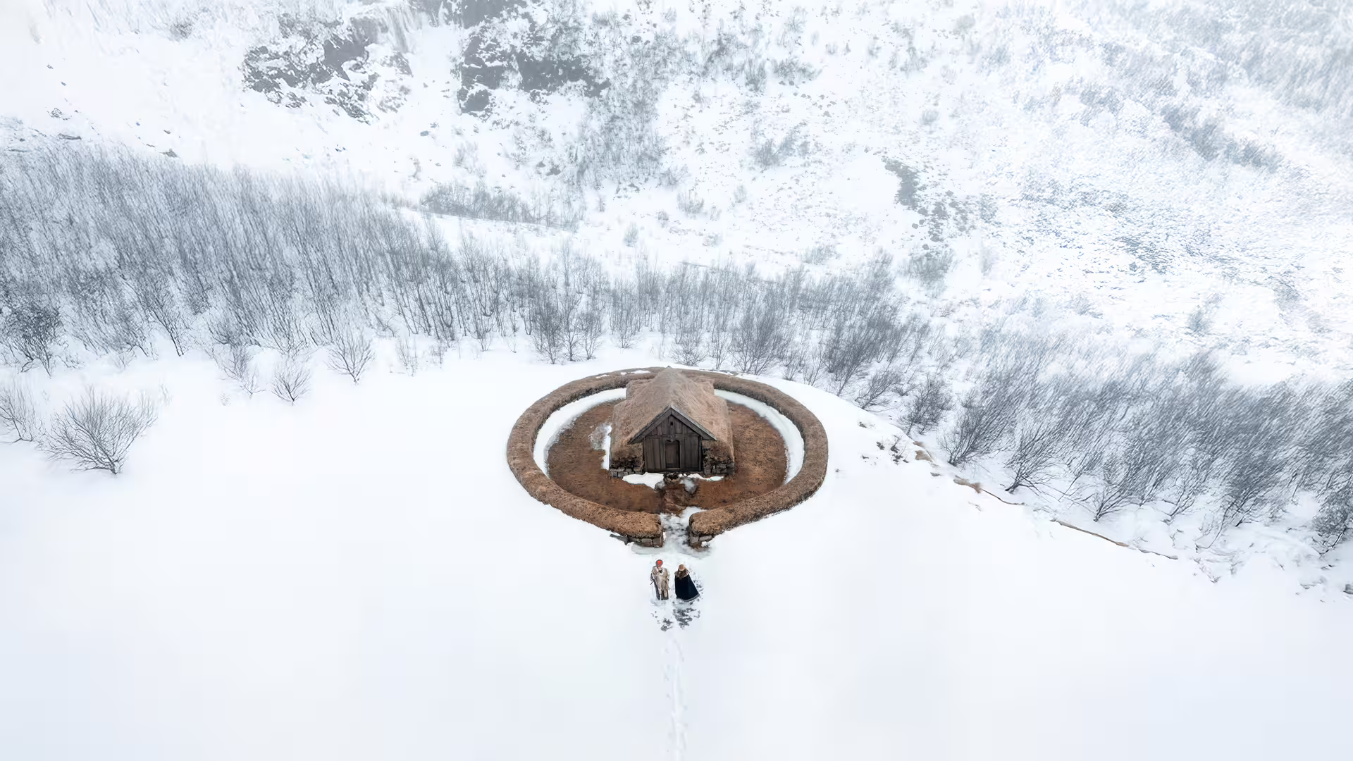 Aerial drone view of ancient Viking longhouse surrounded by snow in Iceland winter landscape tour