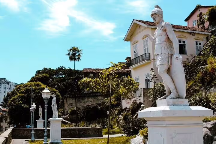 Historic statue and charming architecture in a lush garden setting, highlighting Afro-Brazilian culture in Rio.