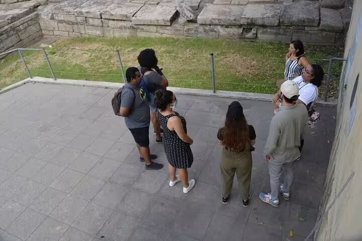 Group of tourists exploring Afro-Brazilian heritage in Little Africa, Rio, with ancient stone ruins in the background.