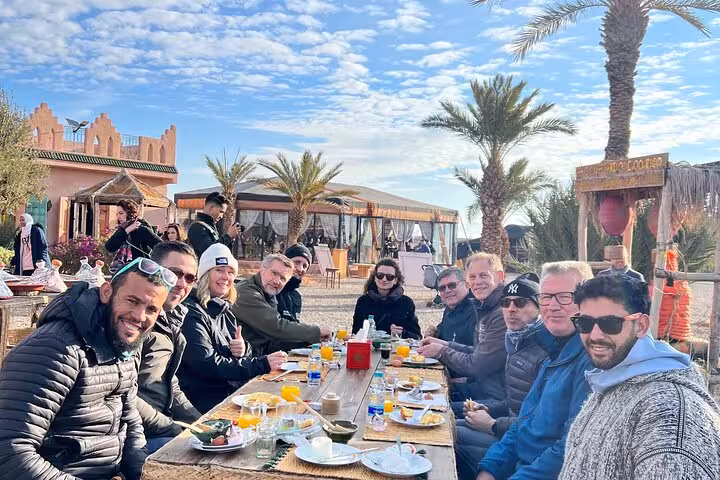 Visitors dining outdoors in the Agafay Desert, Marrakech, soaking in the atmosphere before paragliding and quad biking.