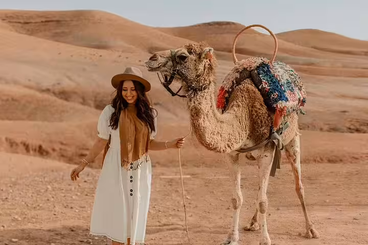 Traveler leading a camel in Agafay Desert dunes, Marrakech sunset camel ride tour with scenic views