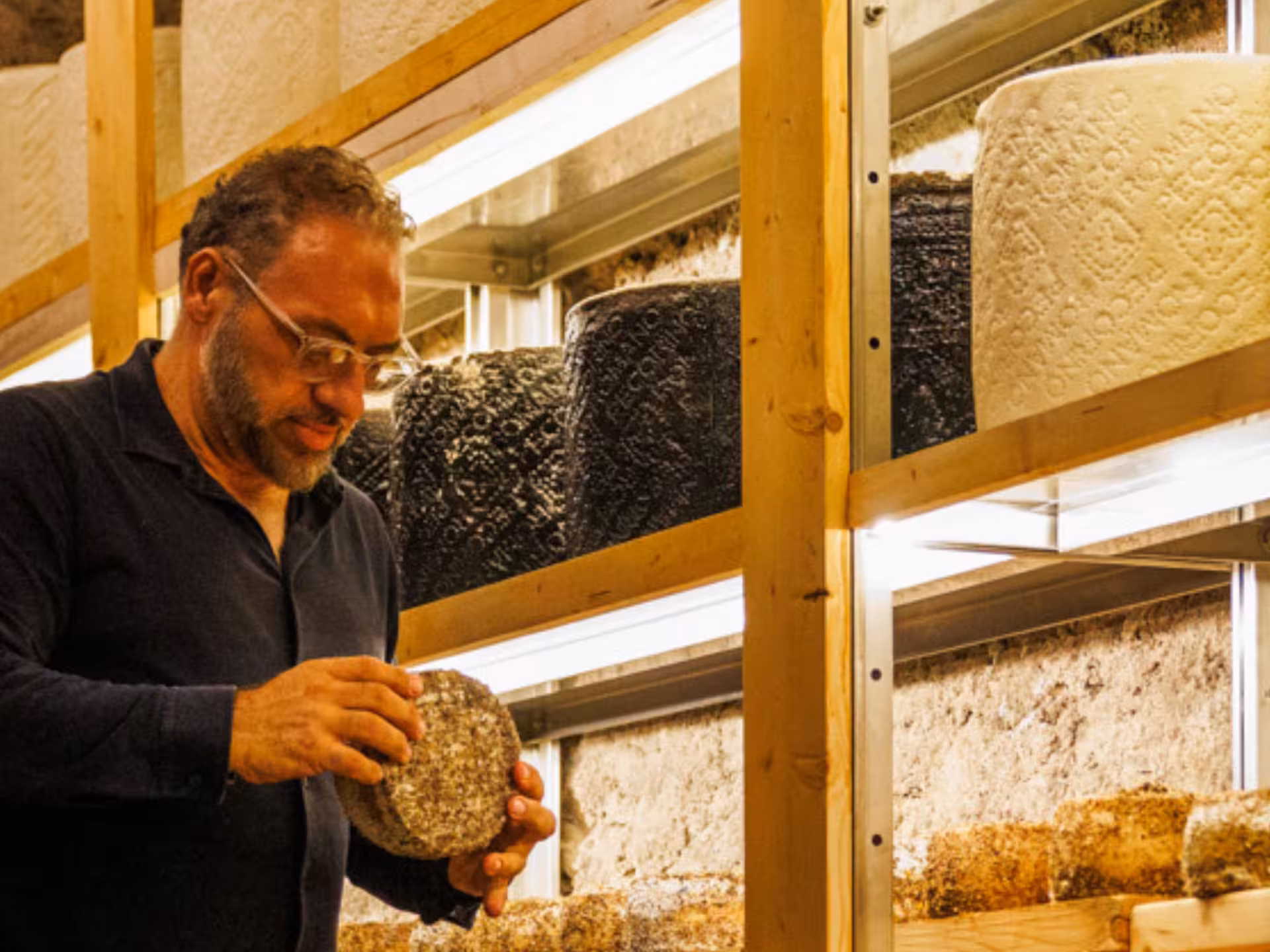 Man inspecting a selection of aged cheeses in an underground Roman cellar for wine and food pairing experience.