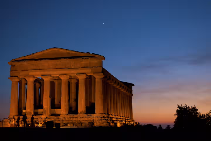Sunset view of Agrigento Valley of the Temples with illuminated Greek temple, a highlight of Taormina day tour