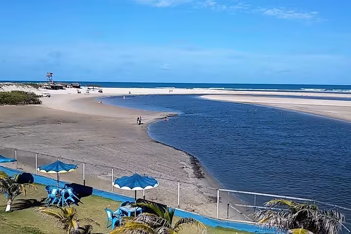 Águas Belas Tour lookout over river meeting the sea, wide sandbar beach and lagoon with umbrellas and palms